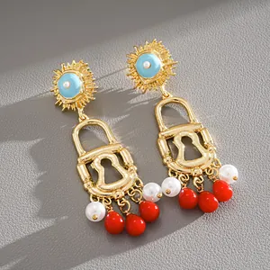 Close-up of vintage gold lock earrings with red beads and white pearls in macro detail.