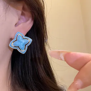 Macro view of light blue star-shaped enamel earring with vintage palace flower design