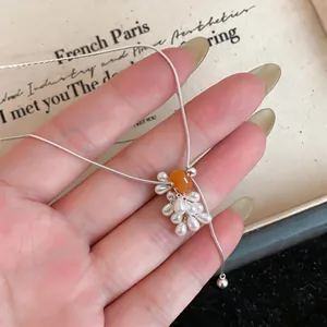 Detail showing the tiger eye stone and pearl grape cluster pendant on a silver chain.