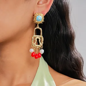 Close-up of vintage gold padlock earrings with colorful pearl and acrylic tassels