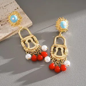 Detailed view of vintage gold padlock earrings with red acrylic tassels and white pearls