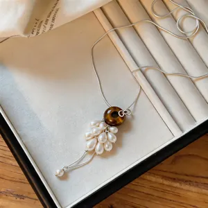 Detailed view of the tiger eye stone donut and pearl grape cluster pendant necklace.