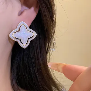 Detailed view of vintage golden star flower stud earring with white glitter enamel