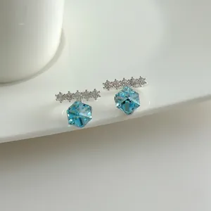 Detail view of silver ear cuff featuring a light blue cube crystal and clear stones