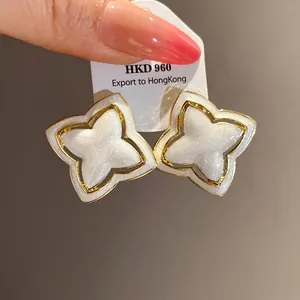 Close-up of vintage gold star flower earrings with white pearlescent oil-drop finish