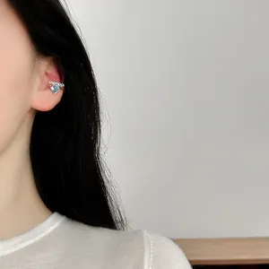 Close-up view of a minimalist blue sugar cube ear cuff worn on a model's ear without piercing