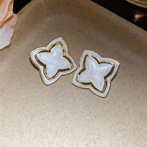 Detailed close-up of vintage star flower stud earrings with pearlescent white enamel finish