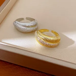 Dettaglio di anelli regolabili placcati in oro e argento con zirconi cubici scintillanti.