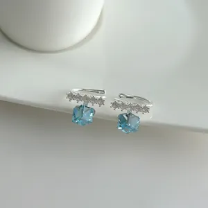 Close-up detail of elegant silver ear cuff featuring a blue cube crystal and tiny white stones.