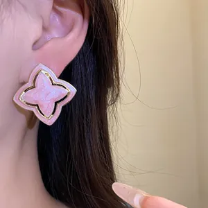 Close-up of a vintage style pink enamel starburst flower earring on model's ear.