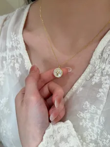 Close-up view of an elegant gold star pendant necklace with zircon and shell inlay
