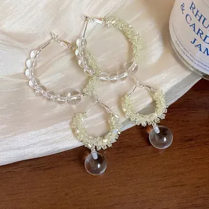 Elegant glass beaded hoop earrings and drop earrings on white fabric background.