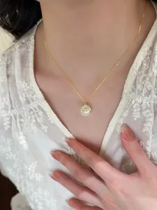 Elegant gold circular pendant necklace with zircon star design on model's neck