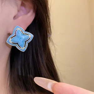 Vintage light blue enamel flower stud earrings with gold trim in retro luxury style