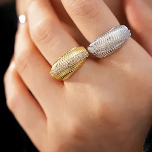 Dettaglio ravvicinato di anelli in zircone testurizzati in oro e argento su dita