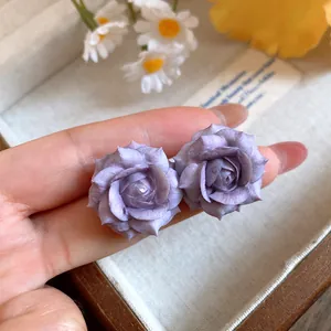 Close-up of elegant purple resin rose flower stud earrings with silver pins in a tray
