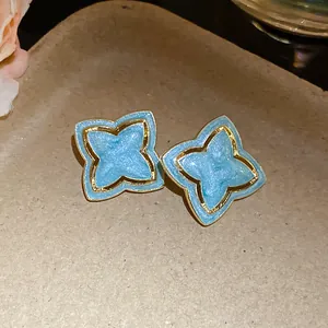 Close-up of vintage light blue star flower stud earrings with an elegant gold trim