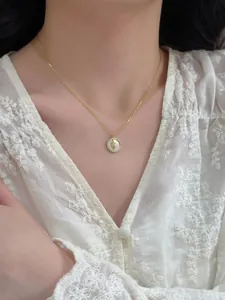 Close-up of a gold necklace featuring a zircon star pendant on a white lace blouse