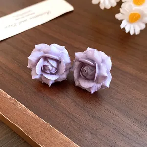 Detailed macro view of elegant purple resin rose flower stud earrings on wood