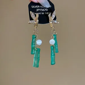 Elegant Chinese style bamboo joint tassel earrings with rhinestones on a warm background