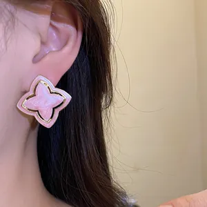 Detail shot of vintage pink enamel flower stud earring with elegant gold-plated rim