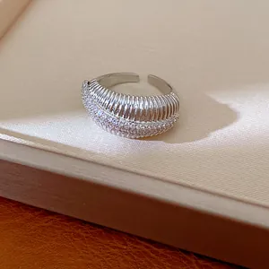 Primo piano di un anello aperto placcato oro 14k con trama e pietre di zircone.