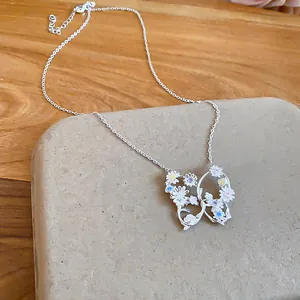 Dettaglio della collana con ciondolo a farfalla e piccoli fiori in zircone