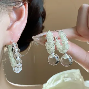 Close-up view of elegant silver needle glass bead hoop earrings featuring clear spherical drops