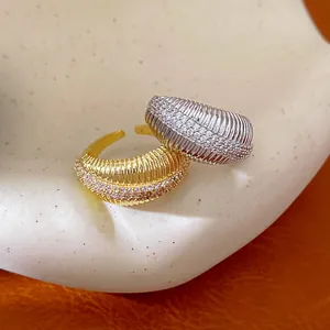 Dettaglio macro di anelli aperti testurizzati placcati in oro 14k e argento con pietre
