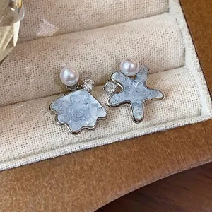 Elegant asymmetric shell and starfish stud earrings with pearls and blue crystal inlay.