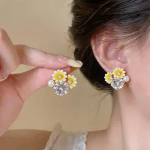 Close-up detail of sweet yellow daisy stud earrings with sparkling zircon and pearl
