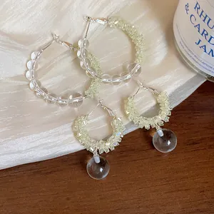 Close-up of glass beaded hoop earrings with crushed stone detail on silk fabric.