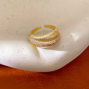 Primo piano di un anello aperto placcato oro 14k con trama a coste e pietre di zircone.