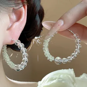 Detailed close-up of clear glass beaded hoop earrings with silver needles for women