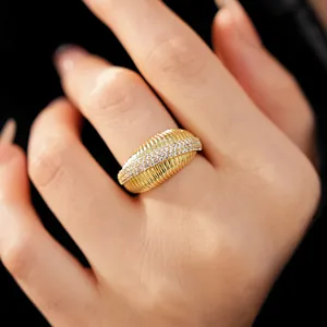 Vista dettagliata di un anello testurizzato in oro 14k con zirconi scintillanti sulla mano