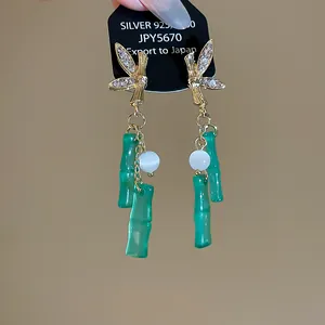 Close-up of elegant New Chinese style earrings with resin bamboo tassels and sparkling rhinestones.