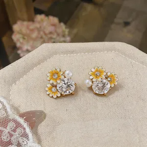 Detailed close-up of zircon and enamel flower pearl earrings on display stand