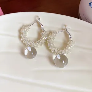 Macro detail of elegant glass bead hoop earrings with a clear glass ball pendant