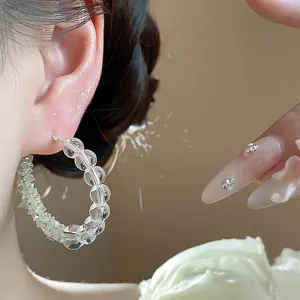 Close-up detail of stylish silver needle glass beaded hoop earrings worn on female ear