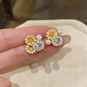 Close-up of elegant daisy flower stud earrings with zircon crystals and faux pearls