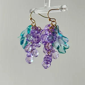Detailed close-up of transparent purple grape bunch drop earrings with green leaves