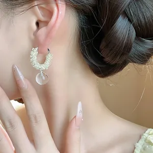 Close-up detail of elegant glass beaded hoop earrings with clear round glass pendant.