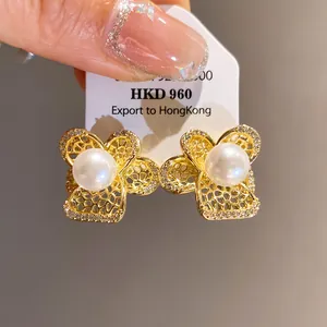 Primer plano de elegantes pendientes de flor dorada con perla blanca y detalles de circonita