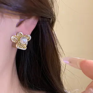 Primer plano detallado de un elegante pendiente de flor hueca con perla central y circón