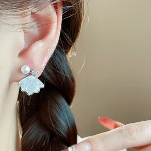 Close-up detail view of elegant fan-shaped shell earring with pearl and zircon