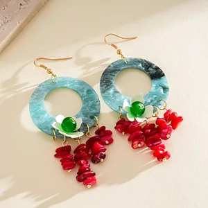 Close-up of vibrant marbled resin earrings with floral accents and red stone tassels