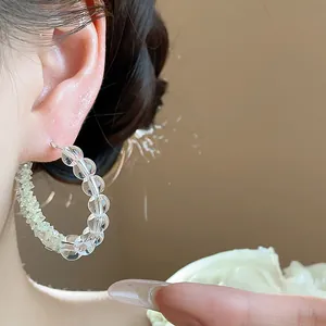 Close-up detail of elegant clear glass beaded hoop earrings worn on a model's ear