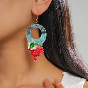 Detail shot of dopamine style marble hoop earrings with floral and red tassel charms