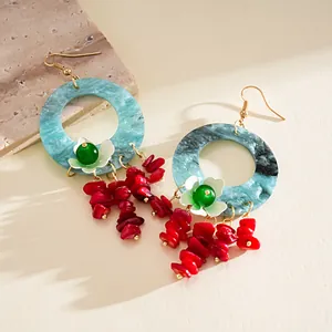Detail of blue marbled resin hoop earrings with red stone tassels and floral charms