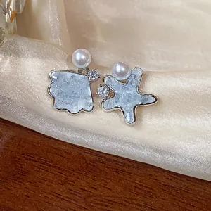 Detailed view of asymmetric shell and star earrings with pearls and zircon stones